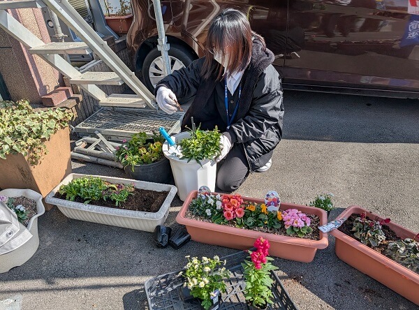 会社ショールームの花を植替えしている女性の写真（前向き）