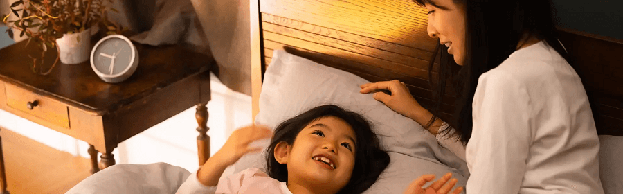 母と子供がベッドで笑顔で安心している画像