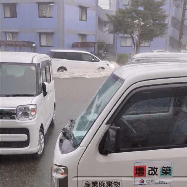 冠水した道路を水しぶきを上げて走る車の画像